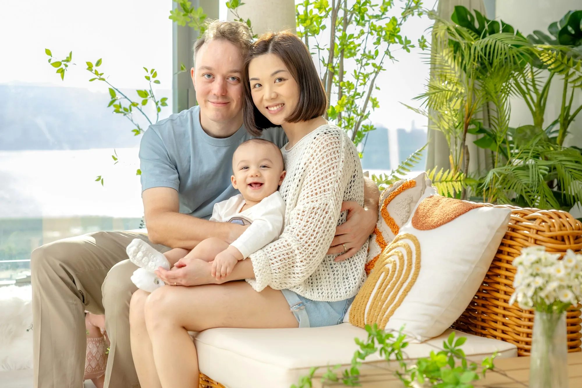 Couple on a porch sofa holding their smiling baby
