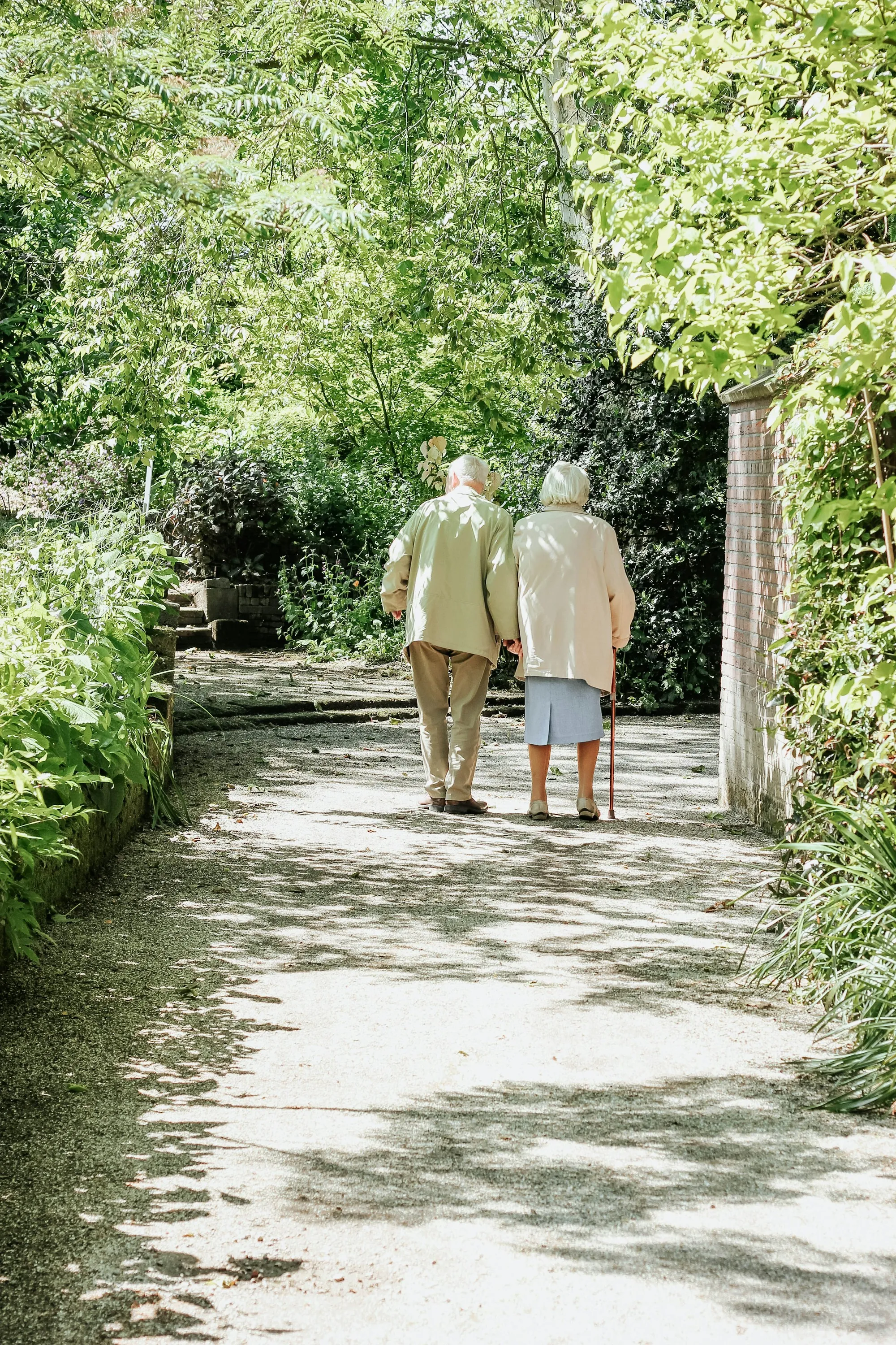 Older couple walking arm in arm down a garden path